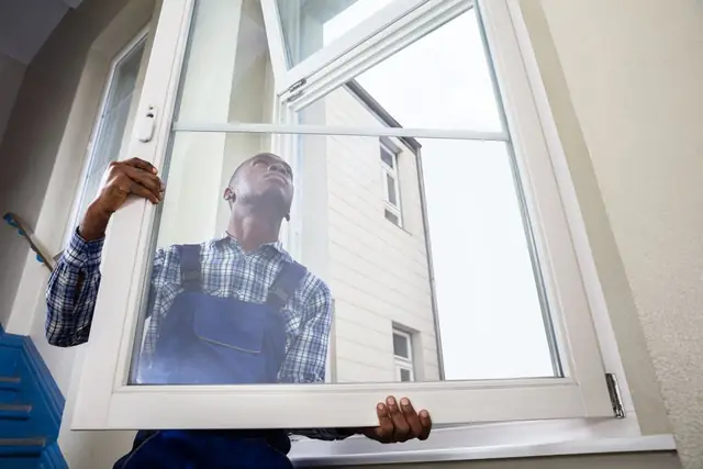 An installer tilting a new casement window into a wall opening